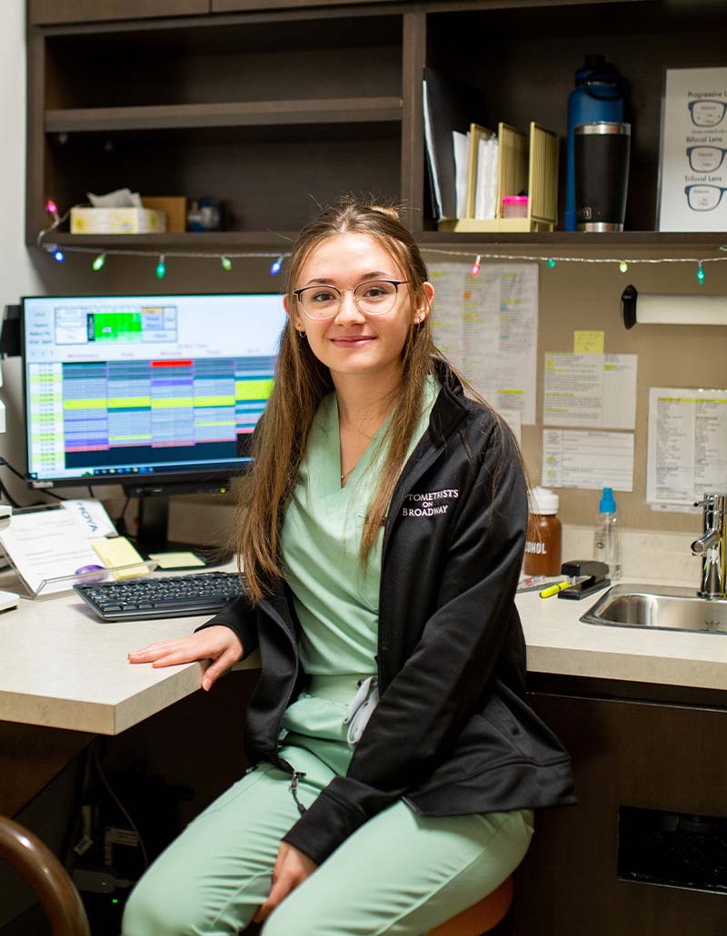 Bethany sitting at desk at optometry office exam room